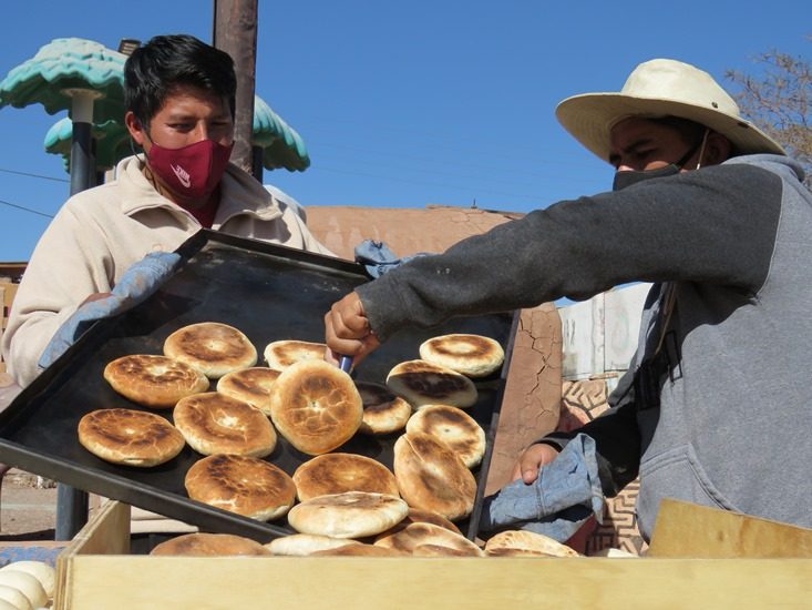 Zwei Einheimische nehmen Brot aus dem Lehmofen