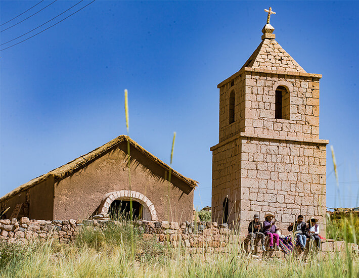 石造りの教会と壁に座っている地元の人々